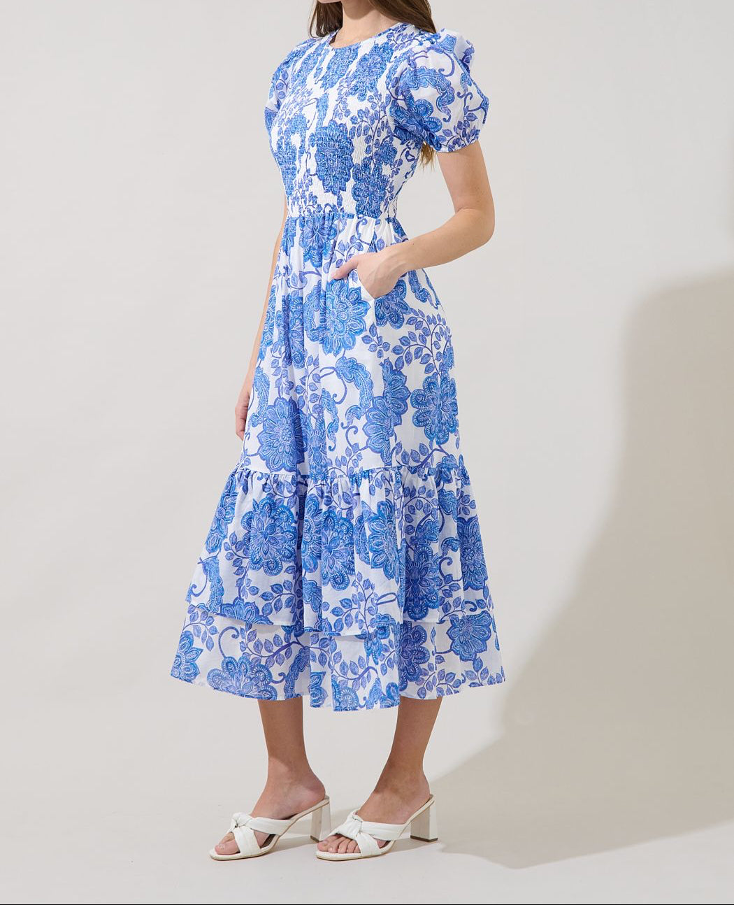 Front view of Sugarlips Aruba white and blue floral midi dress with smocked bodice, puff sleeves, pockets, and tiered hem.