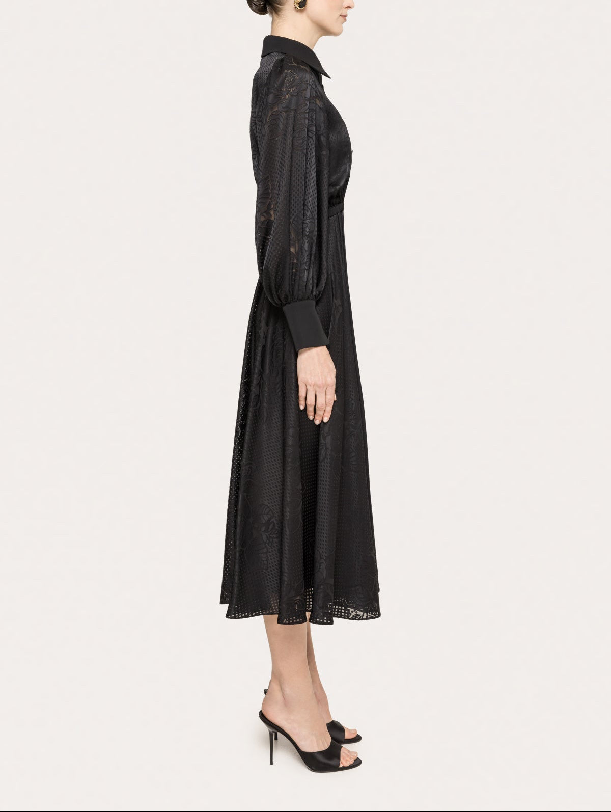 Side view of a black collared midi cocktail dress with long sleeves, slim waist belt, and A-line skirt