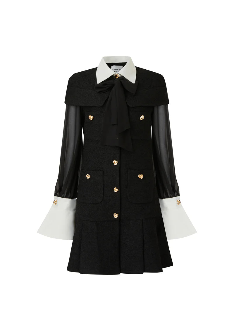 Black pleated mini dress with white collar and flared cuffs, sheer sleeves, bow neck and gold buttons