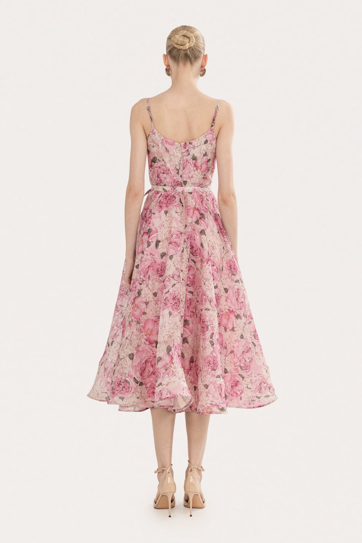 Back view of a pink floral midi dress with adjustable spaghetti straps, defined waist, and full A-line skirt