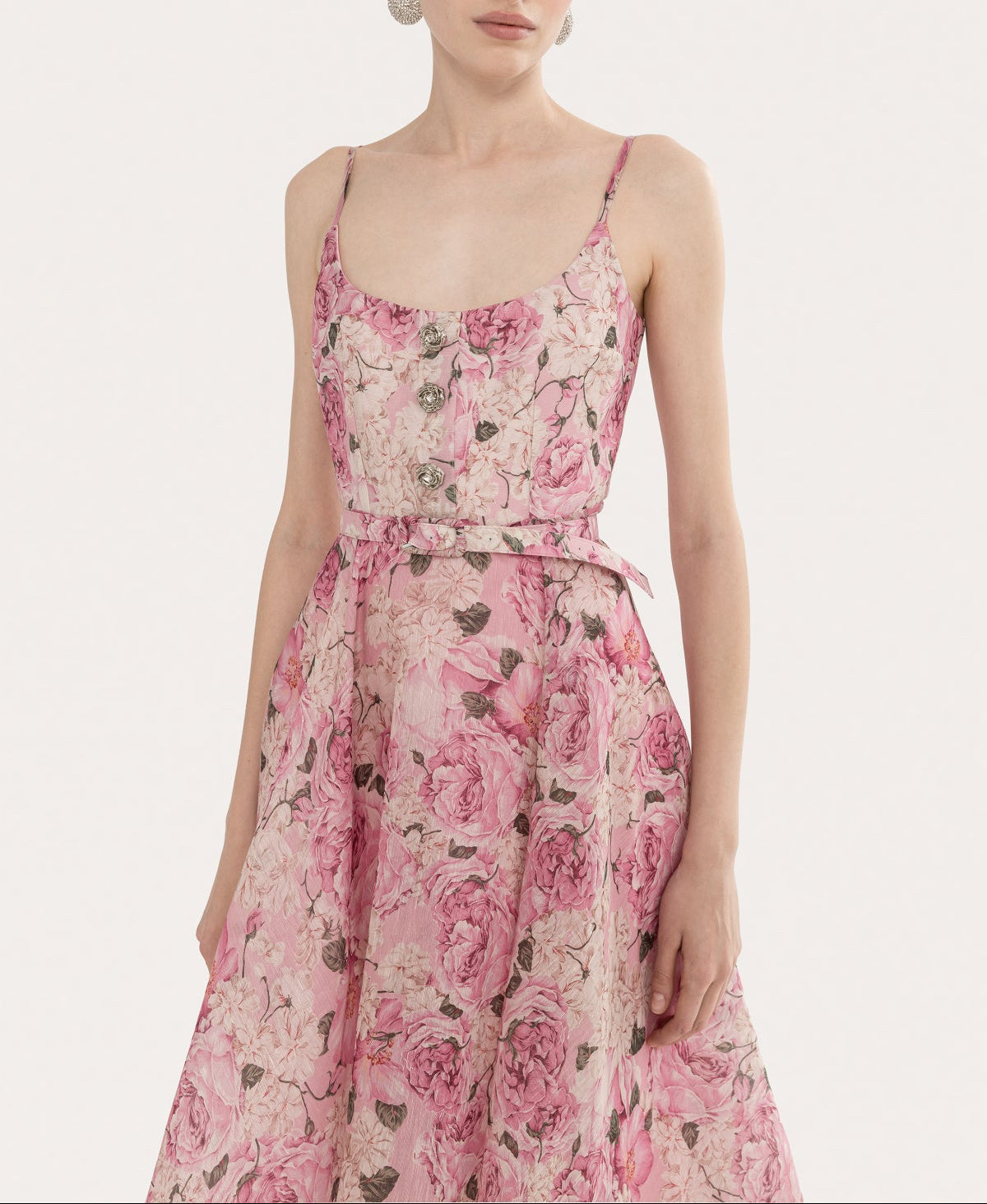 Close-up of a pink floral scoop neckline bodice with decorative floral-inspired buttons and slim straps