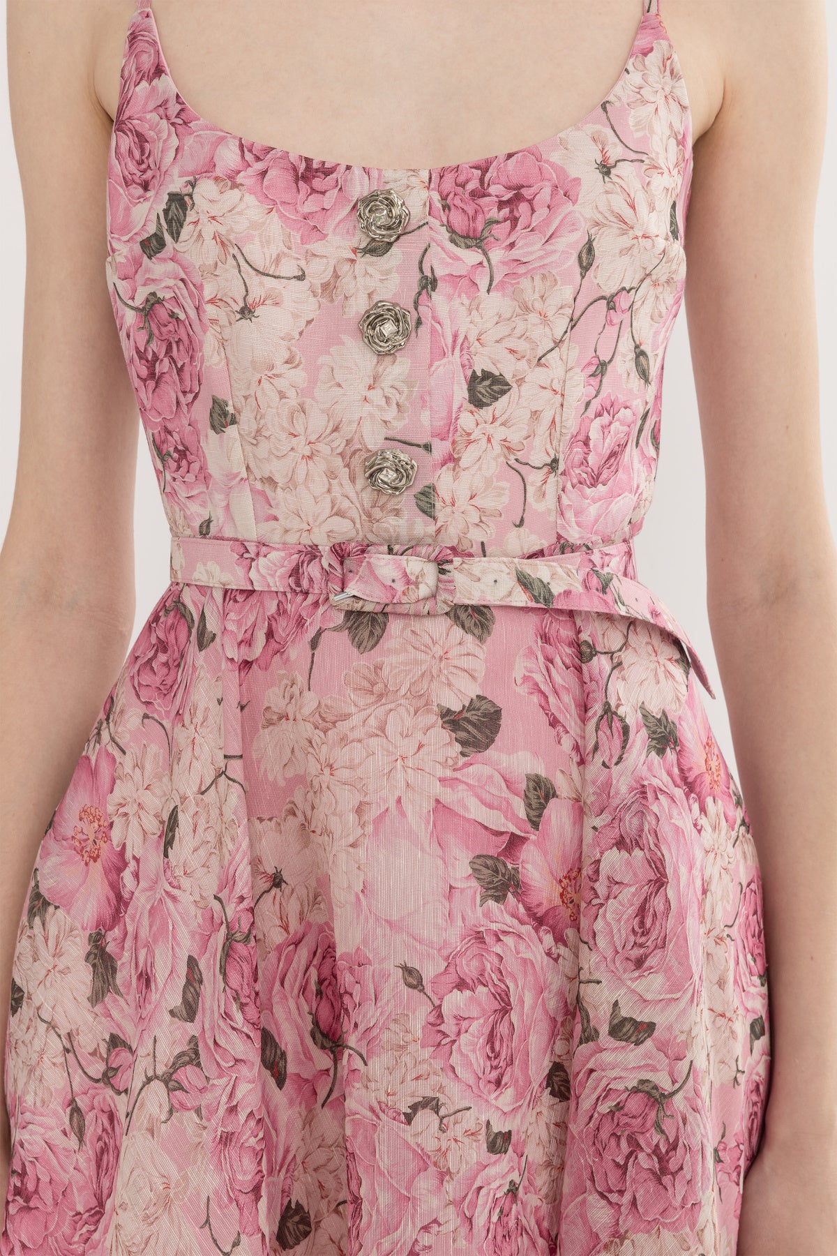 Close-up of the belted waist and floral print bodice on a pink linen-silk midi dress