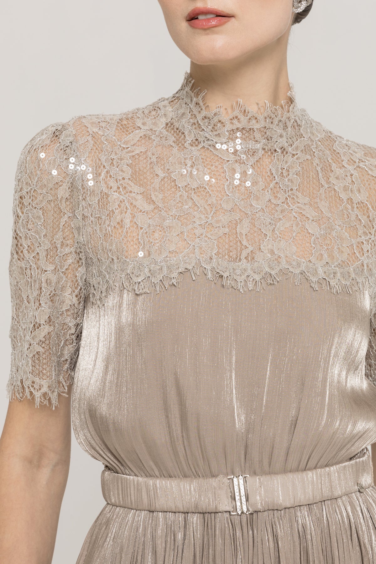 Close-up of champagne lace high neckline with sequined floral lace overlay on a metallic pleated midi dress
