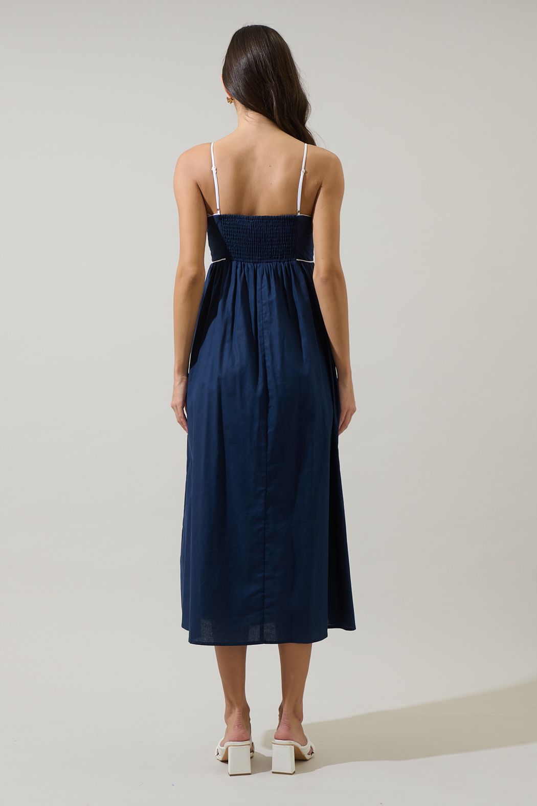 Back view of the Viona navy midi dress with white spaghetti straps, smocked bodice and straight midi hem.