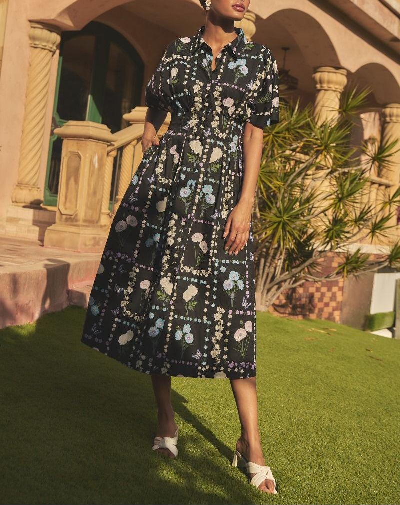 Outdoor lifestyle view of Wilderra black pastel floral midi dress styled with white heeled sandals