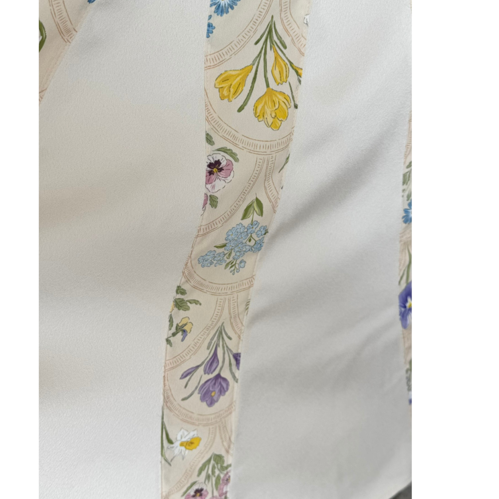 Close-up of paneled cream skirt and floral print detail on Nora Noh midi dress