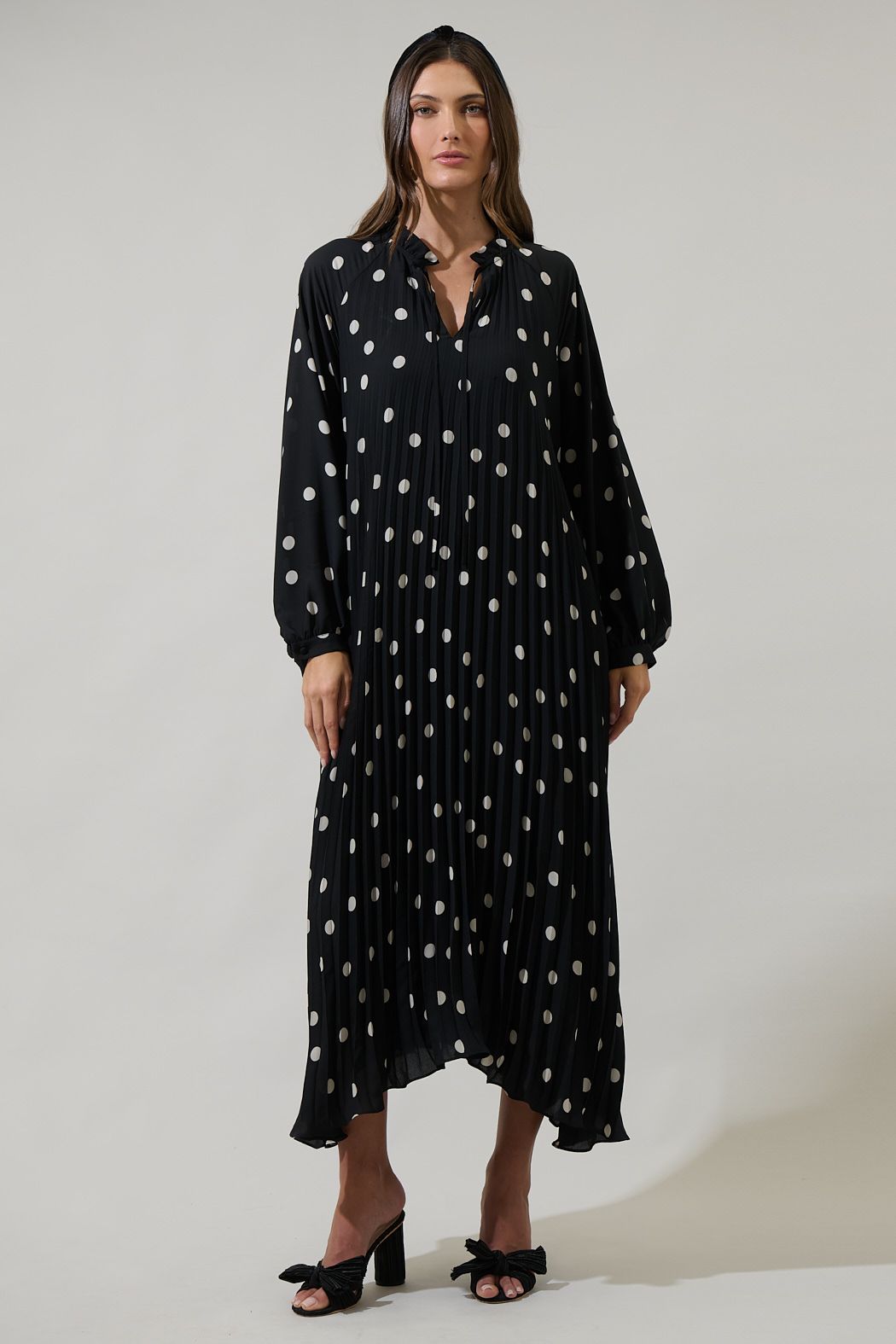 Black polka dot pleated midi dress with long sleeves and classic flowing silhouette