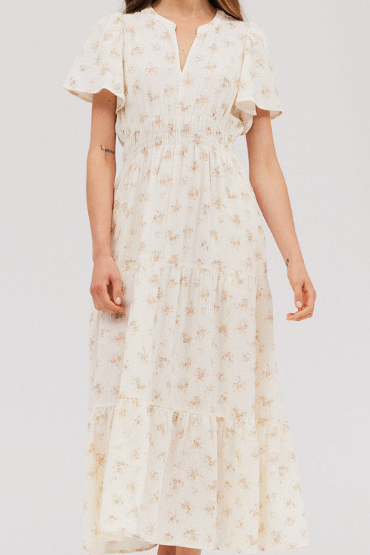 Close front angle highlighting pockets, smocked waist, and flutter sleeves on the sweater‑friendly floral midi dress.