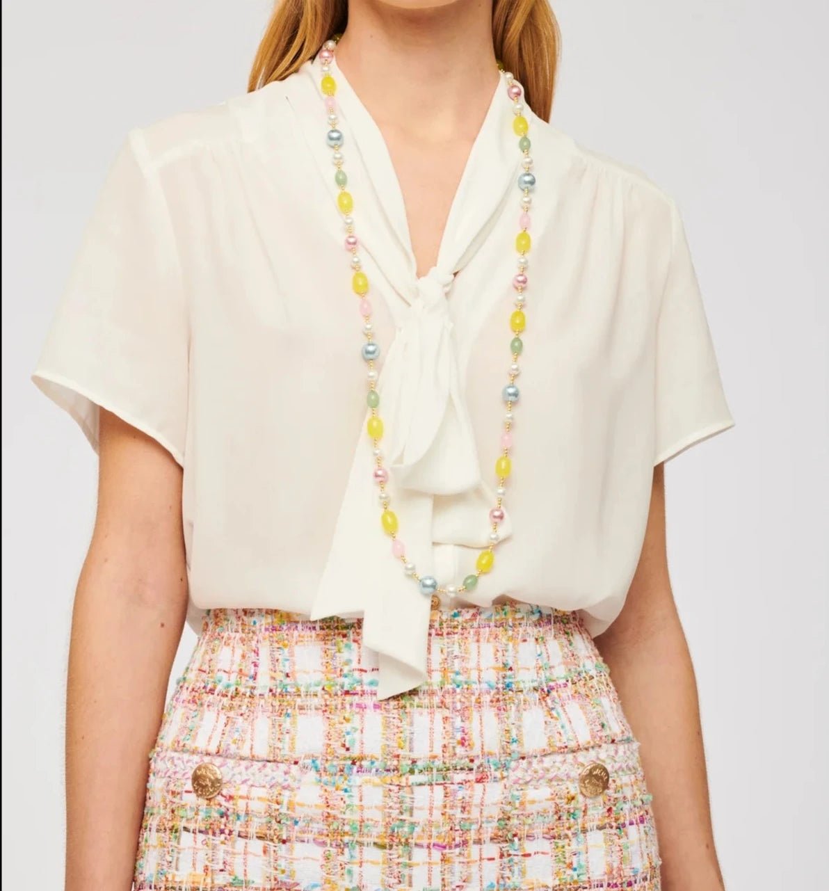 Close-up of Weill Paris multicolor pearl bead long necklace with pastel yellow, blue, pink, and green beads on a cream blouse