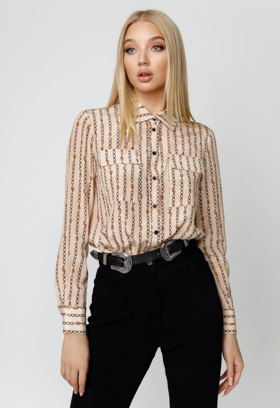 Model wearing a cream and gold chain-print silk bodysuit blouse with long sleeves, a button front, and chest pockets.
