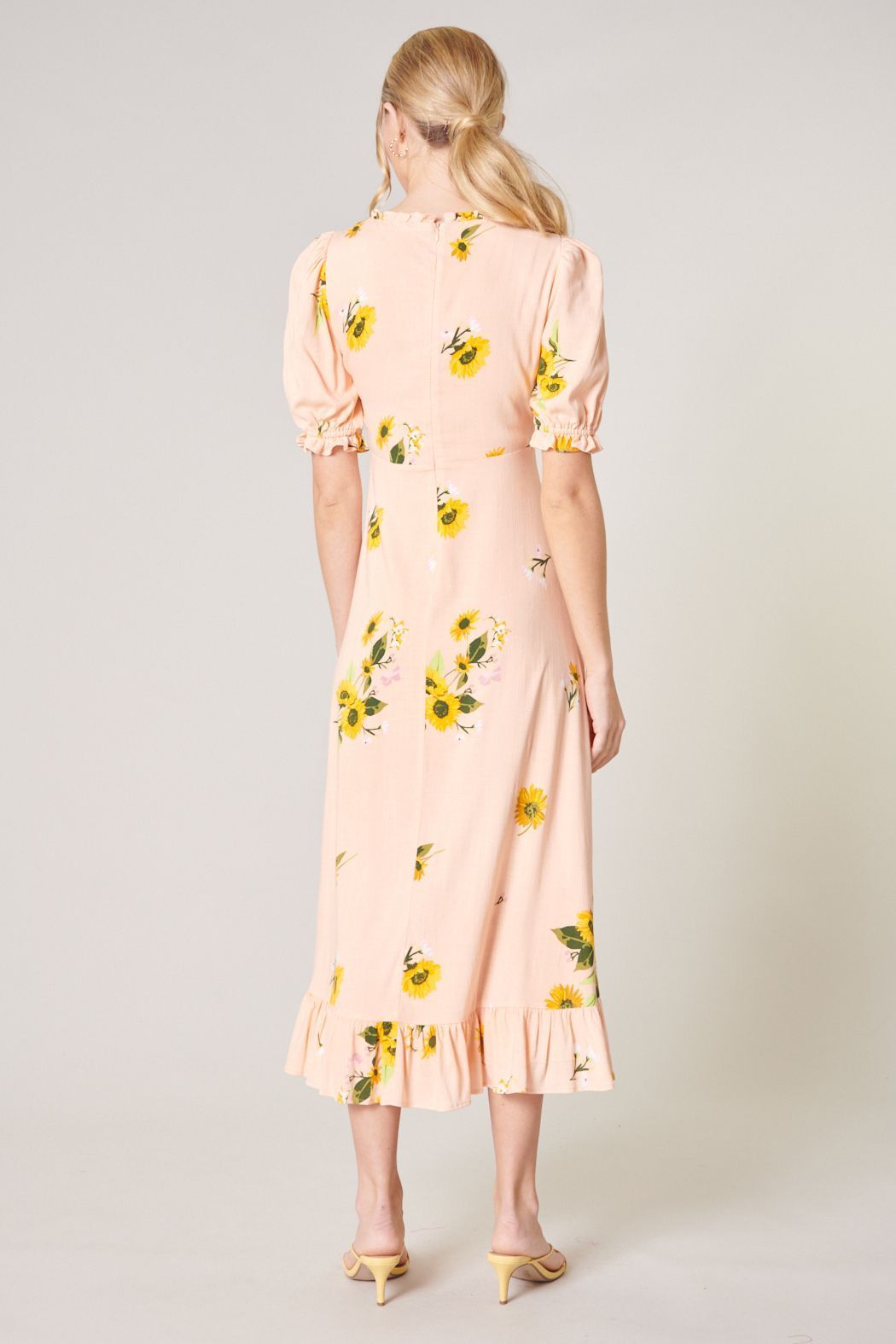 Back view of yellow floral midi dress with defined waist and flowing skirt
