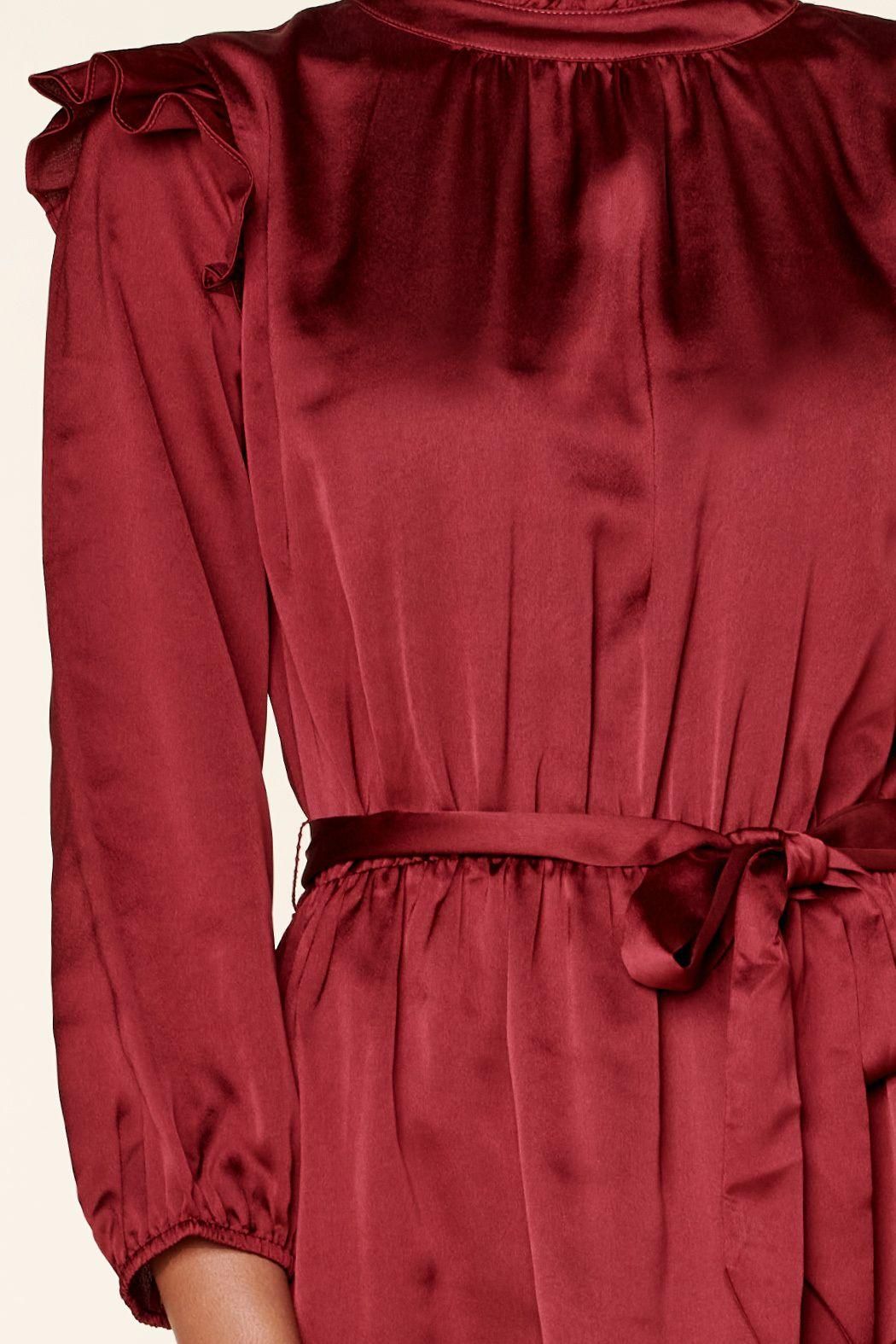 Close-up of burgundy satin dress with asymmetrical flounce hem and sleeve detail