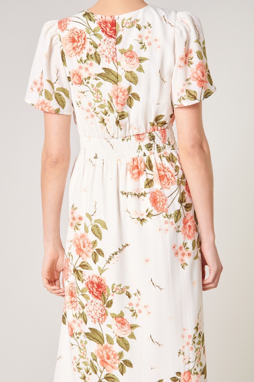 Close-up of keyhole back and smocked waist on ivory floral midi dress