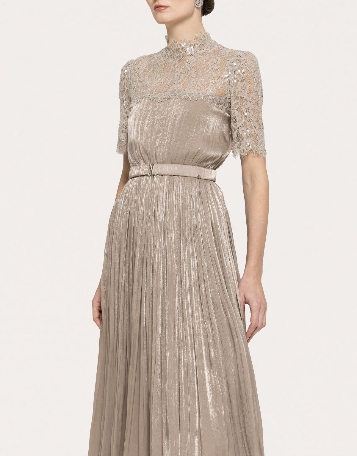 Angled view of a champagne lace high neck midi occasion dress with metallic pleated skirt and fitted waist