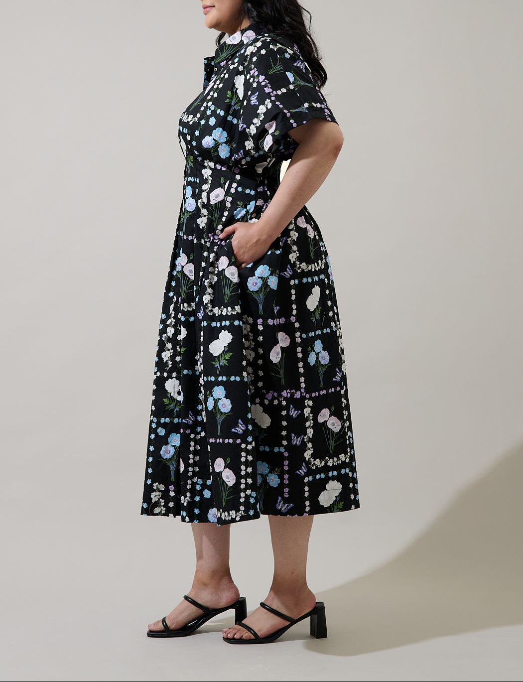 Curve fit side view of black pastel floral midi dress with pocket and fit-and-flare silhouette