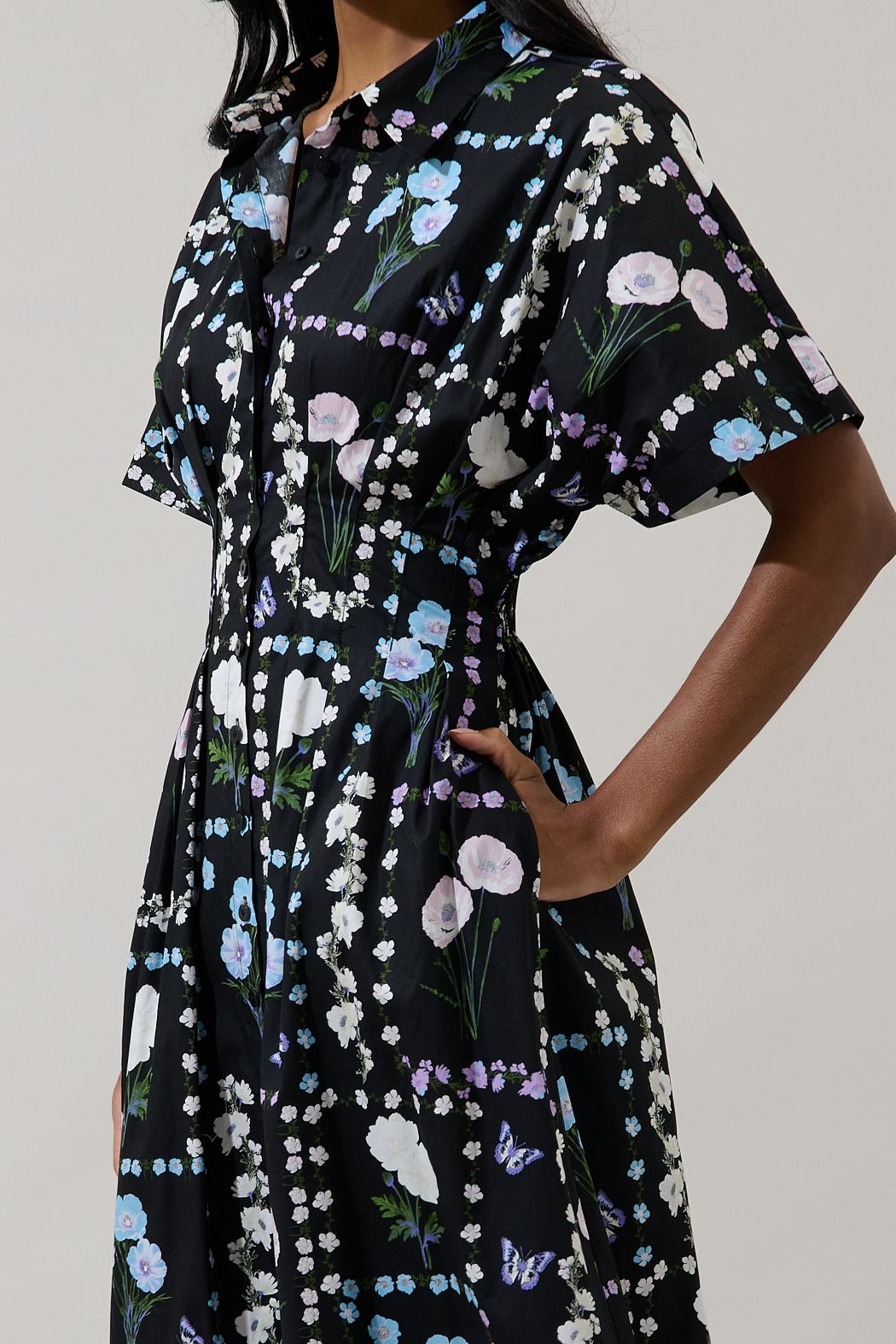 Close-up of black floral cotton midi dress showing collar, button placket, short sleeve and side pocket