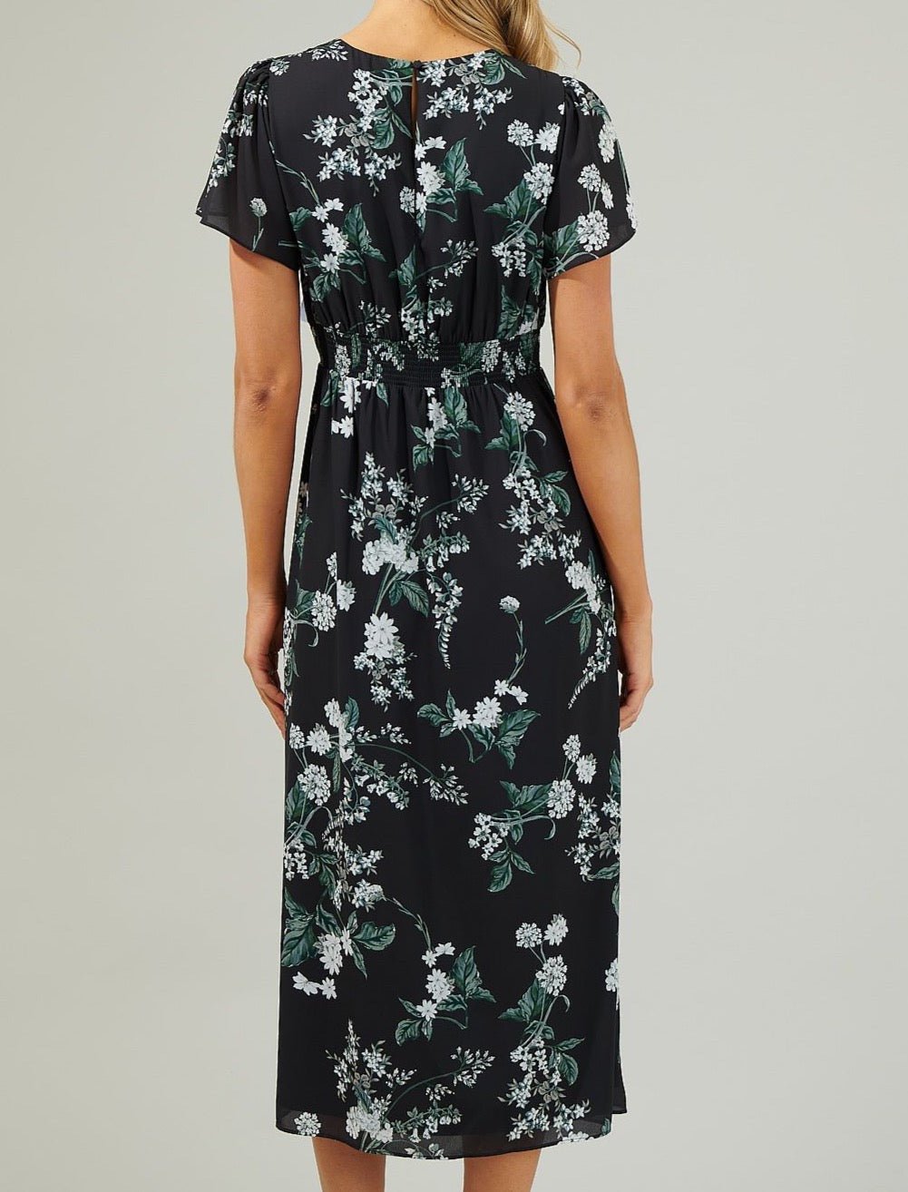 Back view of a black floral midi dress with a smocked back waist and keyhole closure