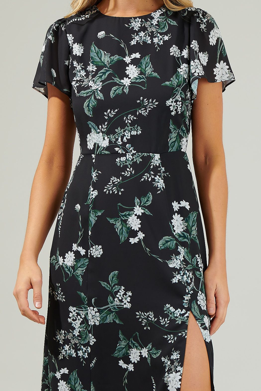 Close-up of the floral print, flutter sleeves, and waist seam on a black midi dress