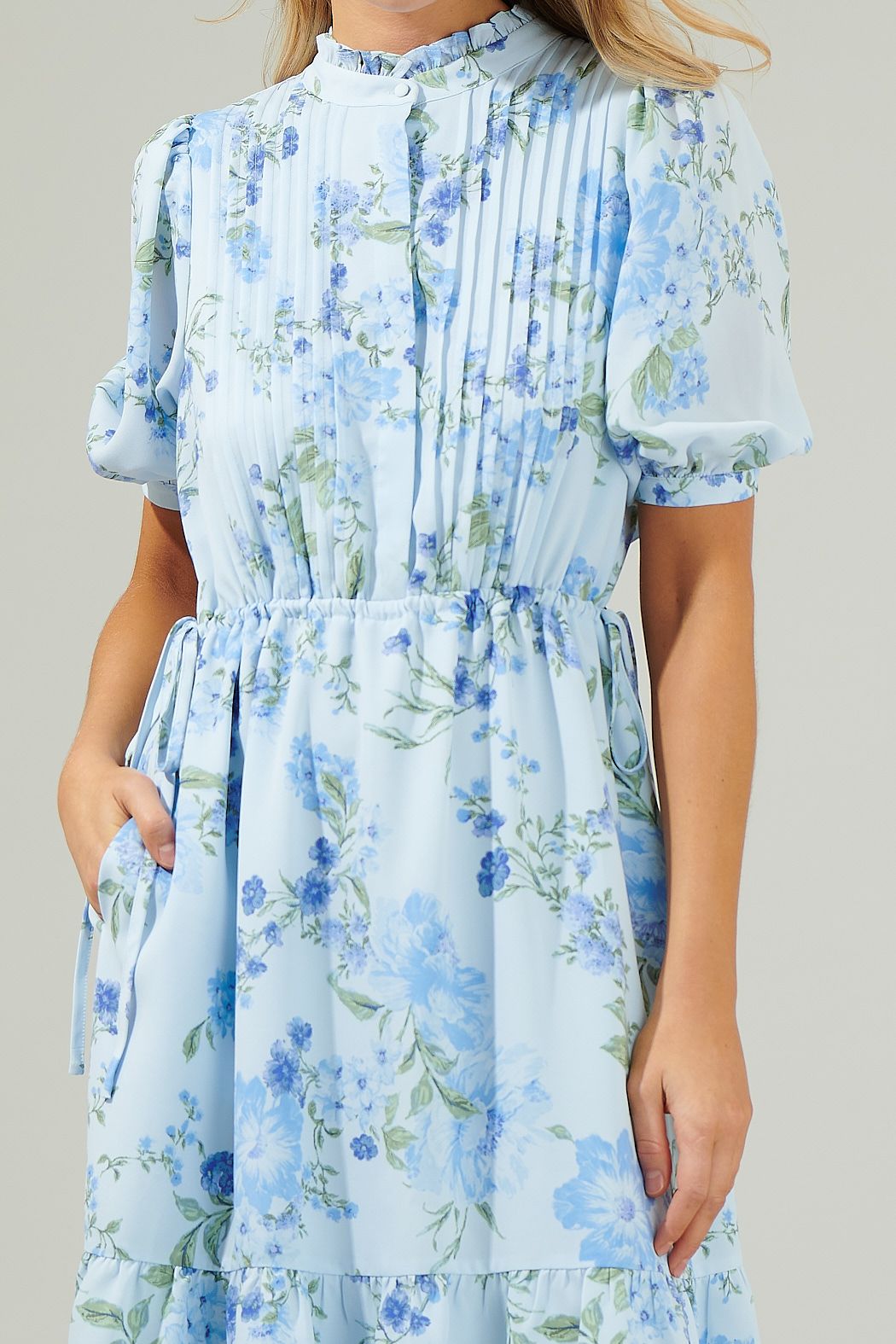 Close-up of pleated bodice, light blue floral print, and drawstring waist on midi dress
