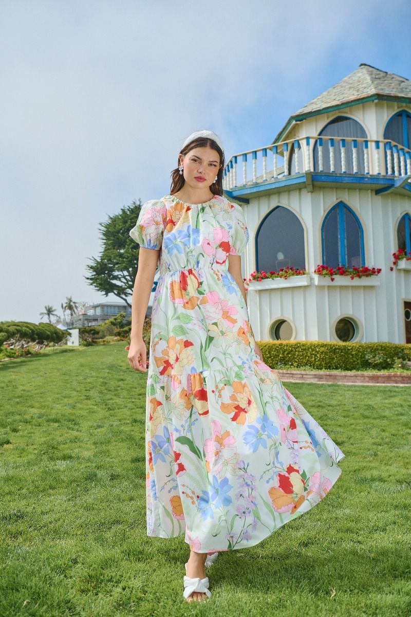 Model wearing a pastel floral cotton maxi dress with puff sleeves in a garden setting