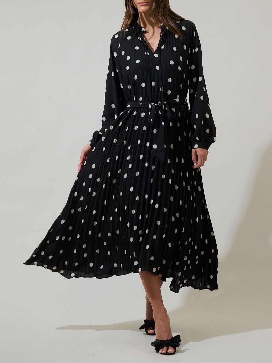 Black polka dot pleated midi dress with long sleeves and tie waist front view