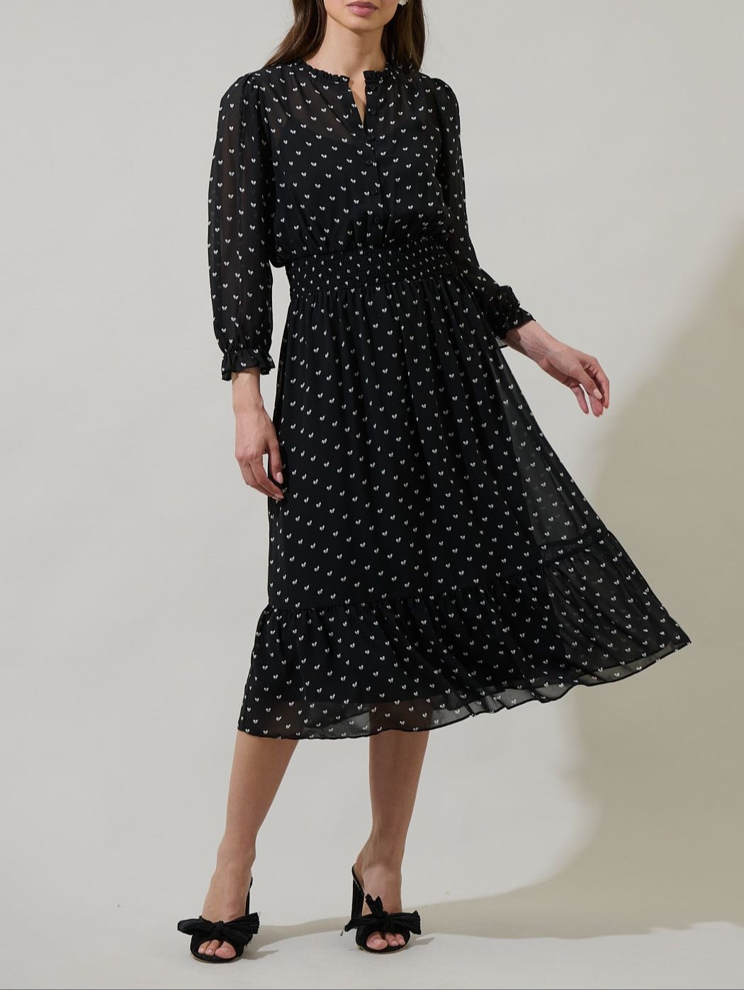 Black bow print smocked midi dress with long sheer sleeves and ruffle neckline front view