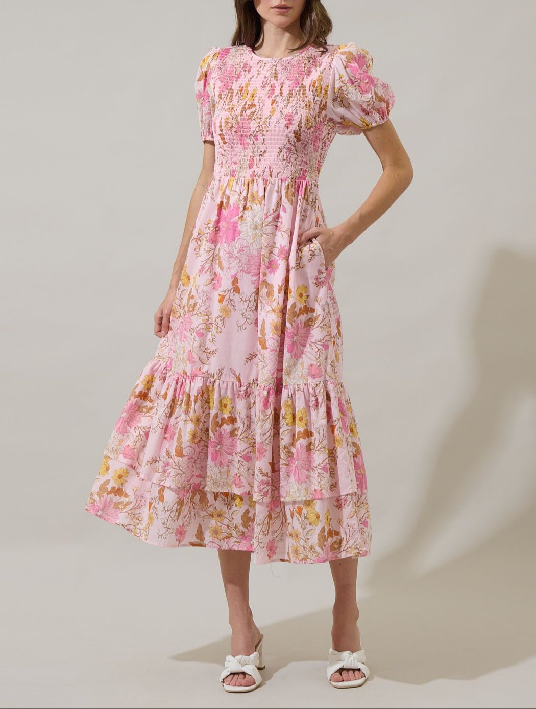 Pink floral smocked midi dress with puff sleeves, pockets, and tiered skirt front view