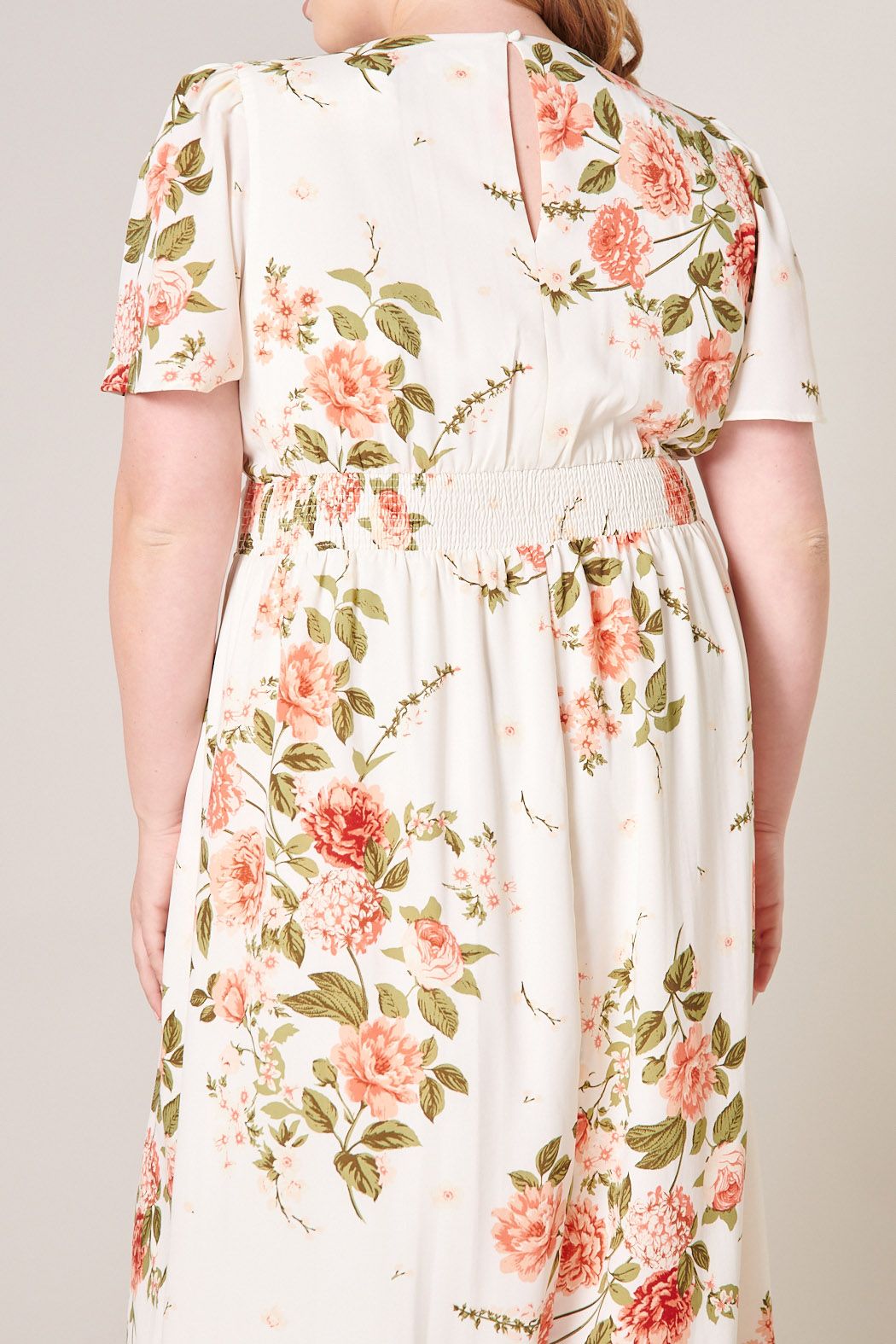 Close-up of plus size ivory floral midi dress with smocked waistband and keyhole back