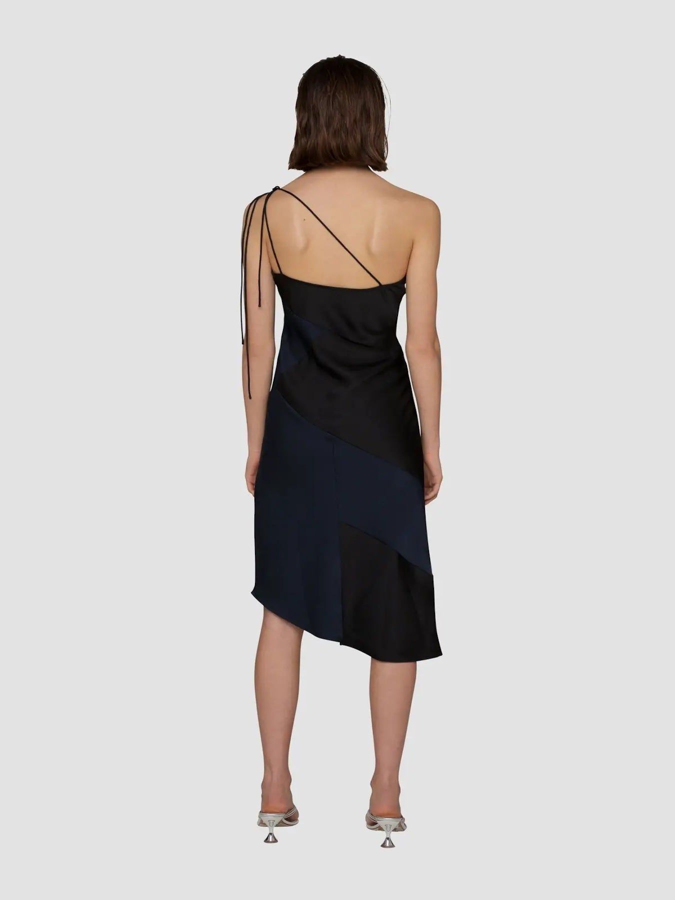 Back view of black and navy colorblock satin midi dress with asymmetric straps