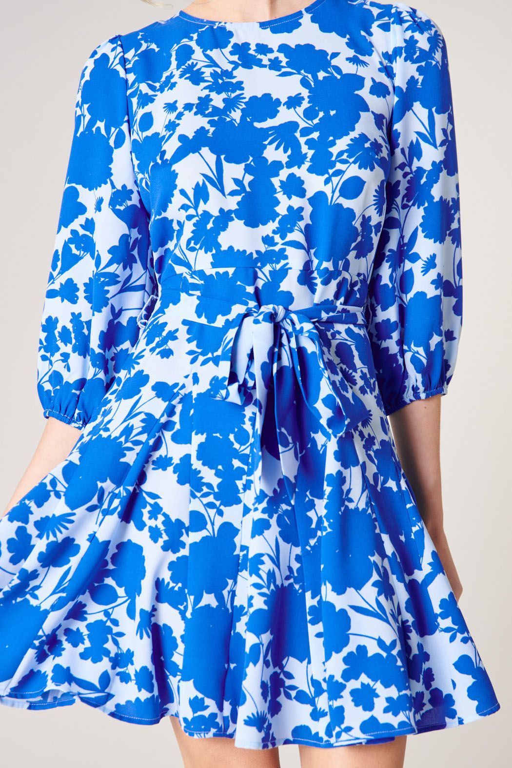 Close-up of blue floral print, jewel neckline, and tie waist on mini dress